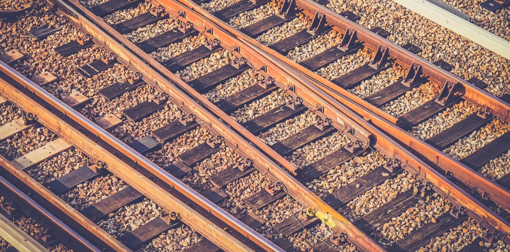 Rusty-hued closeup photograph of tracks running through a train yard